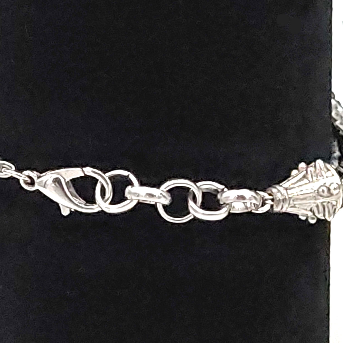 Silver colored end caps, extender chain, and lobster clasp of a black and light gray seed bead bracelet / anklet on a black velvet display stand.