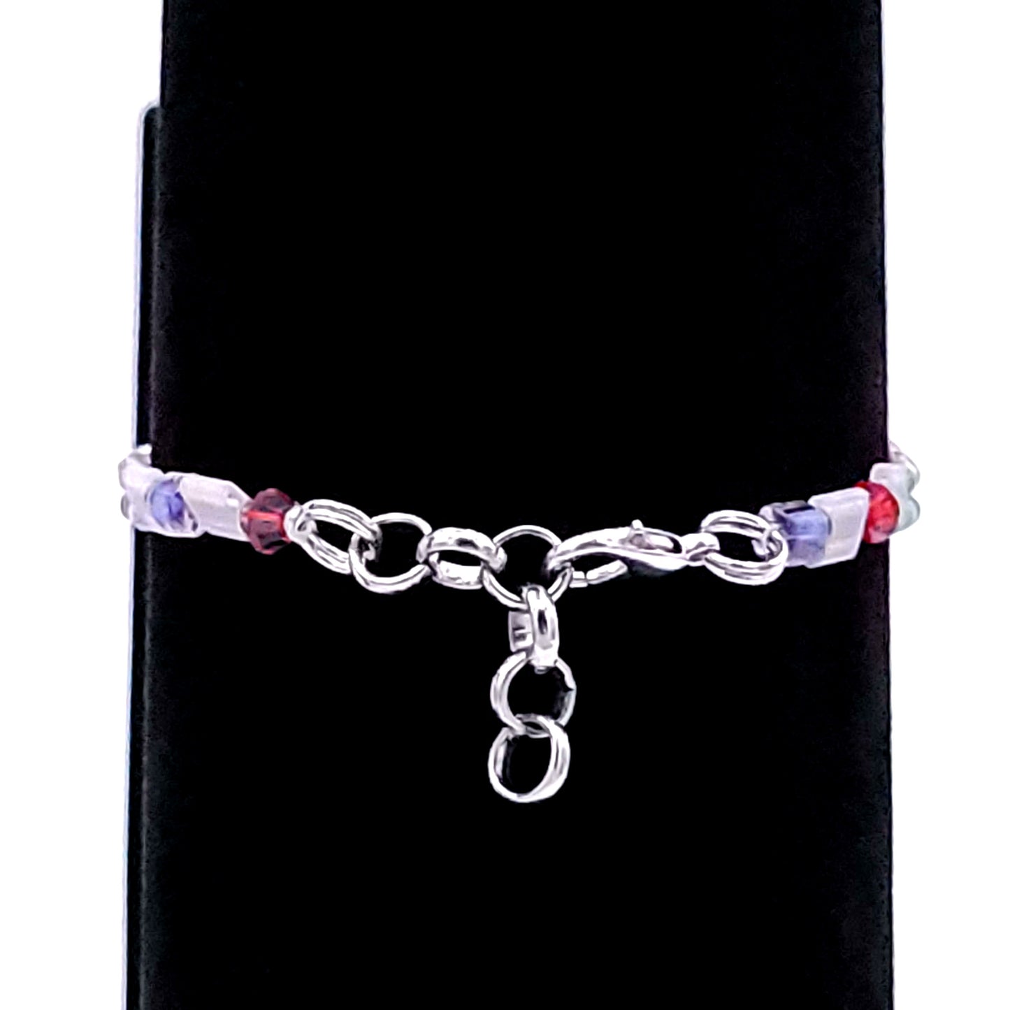 Silver tone clasp of a bracelet made of red, white, and blue beads on a black velvet display.
