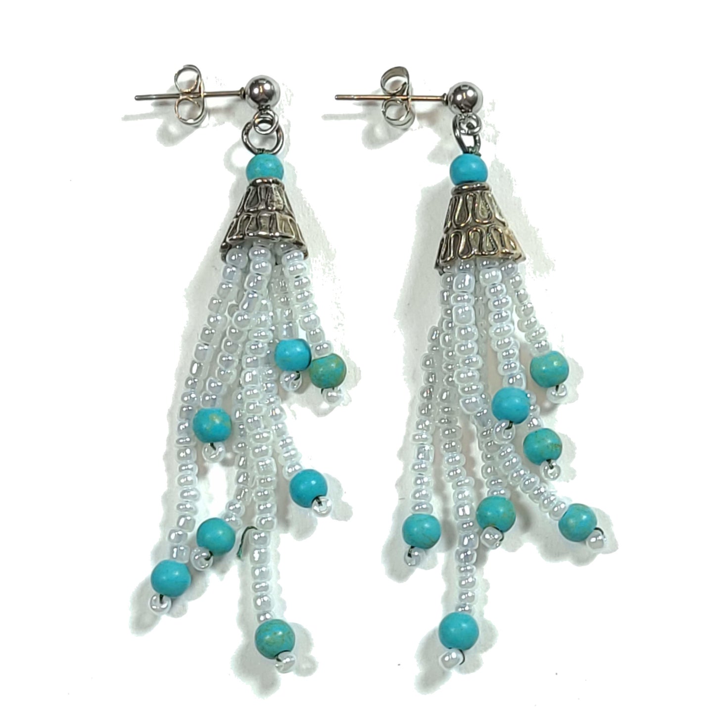 Dangly earrings made of white seed beads with blue beads on the end of each strand. Silver colored end caps and earring hooks.