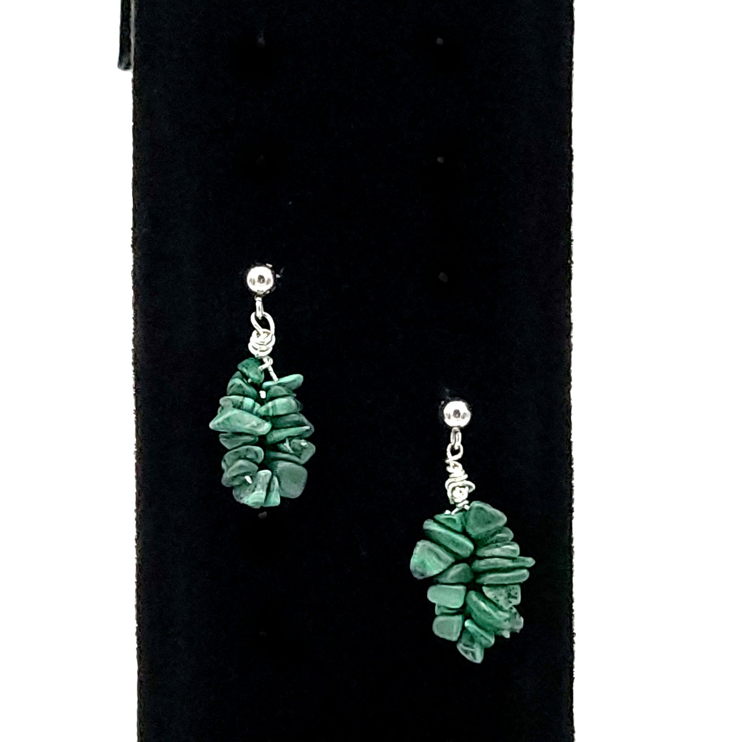Close up of earrings made on silver tone posts with malachite chips on a black velvet display