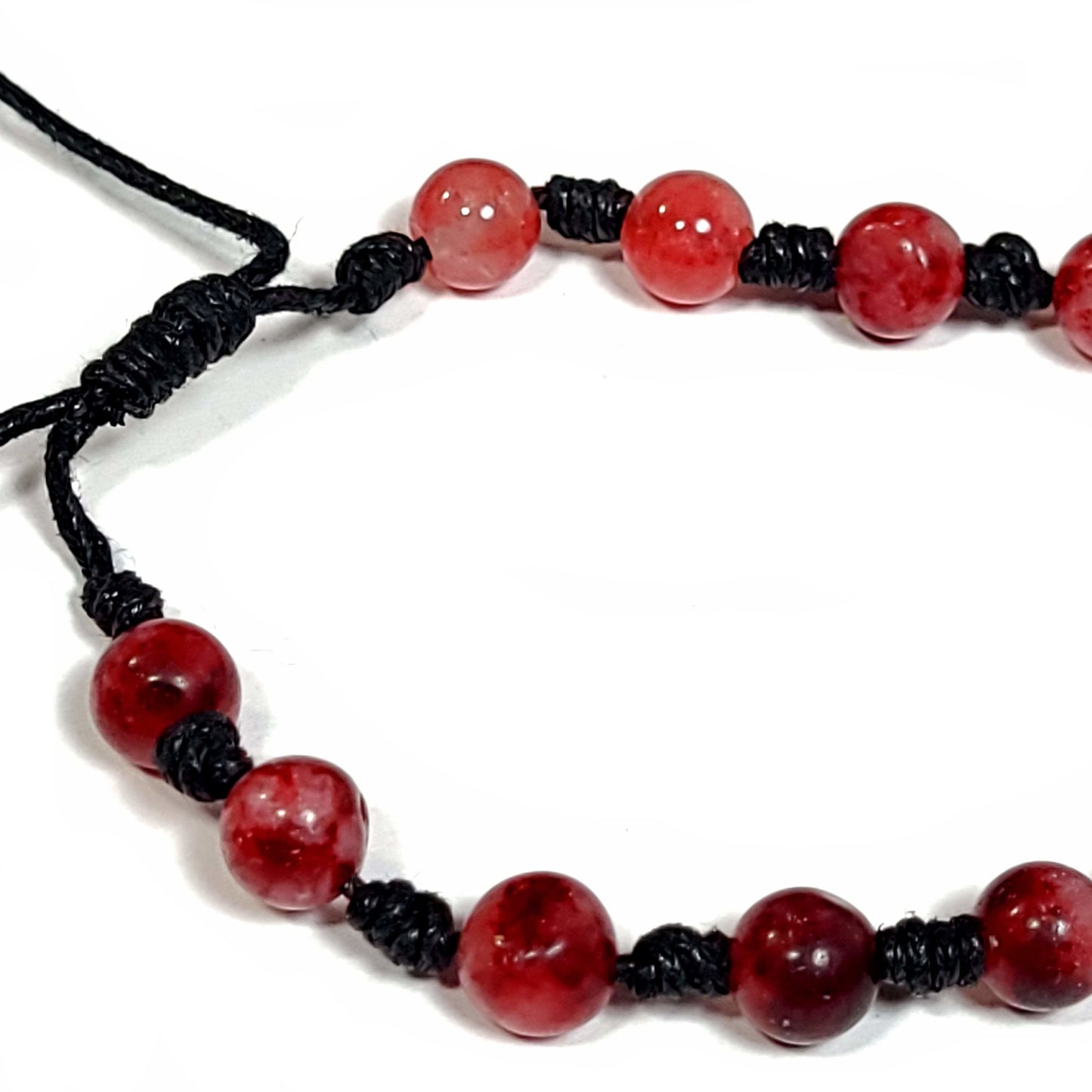 Handmade knotted bracelet of red stone beads with white and a little black running through them, Can be worn as a bracelet or anklet. Adjustable slip knot makes adjusting