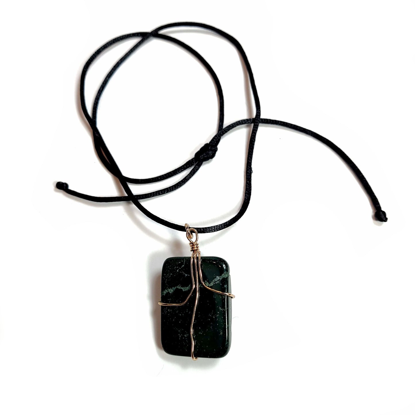 Rose gold colored wire wrapped dark green Jasper stone. Comes with a black satin cord with an adjustable slip knot. Stone has a natural imperfection on the face.