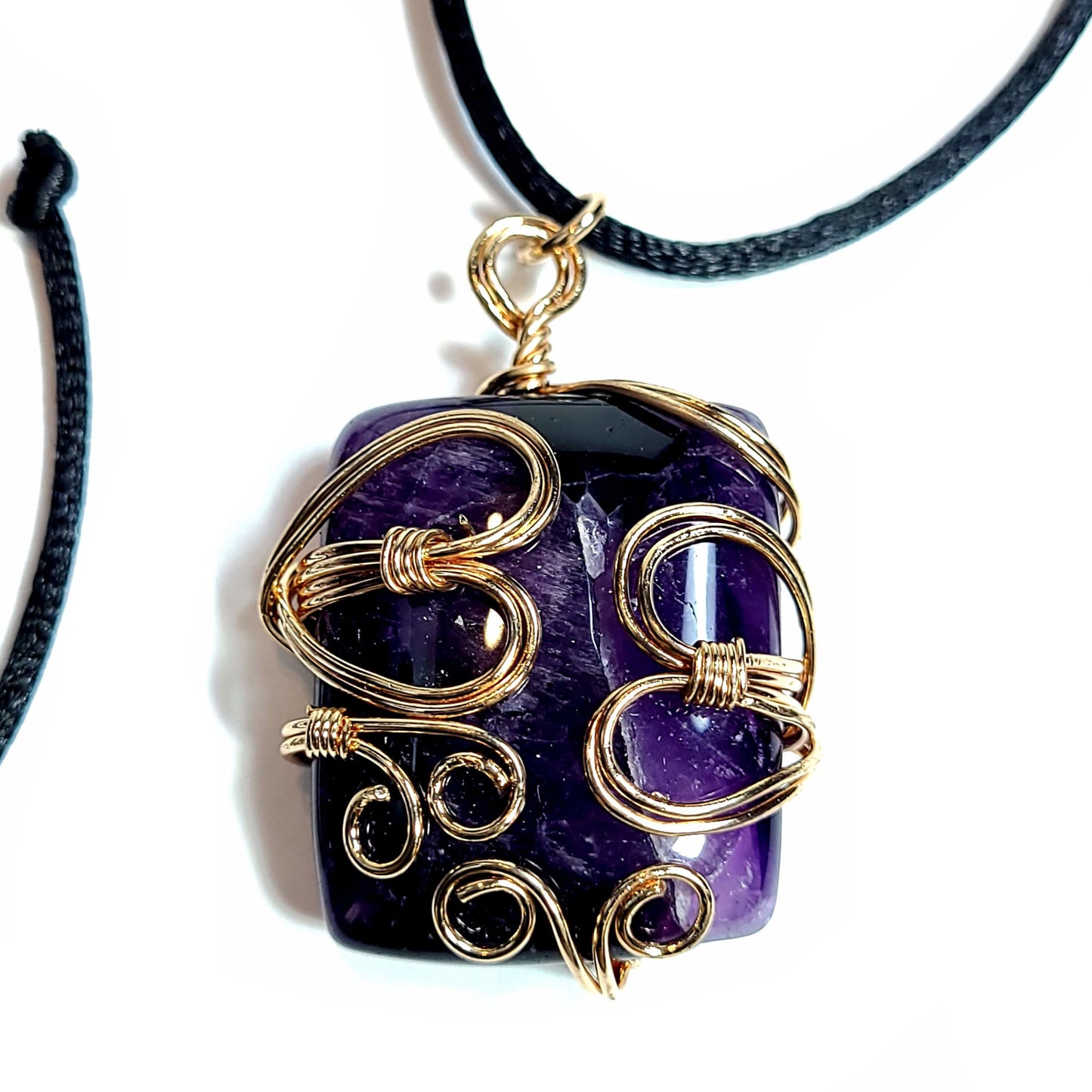 Rose gold colored wire wrapped Very Dark Purple Amethyst. Comes with a black satin cord with an adjustable slip knot.