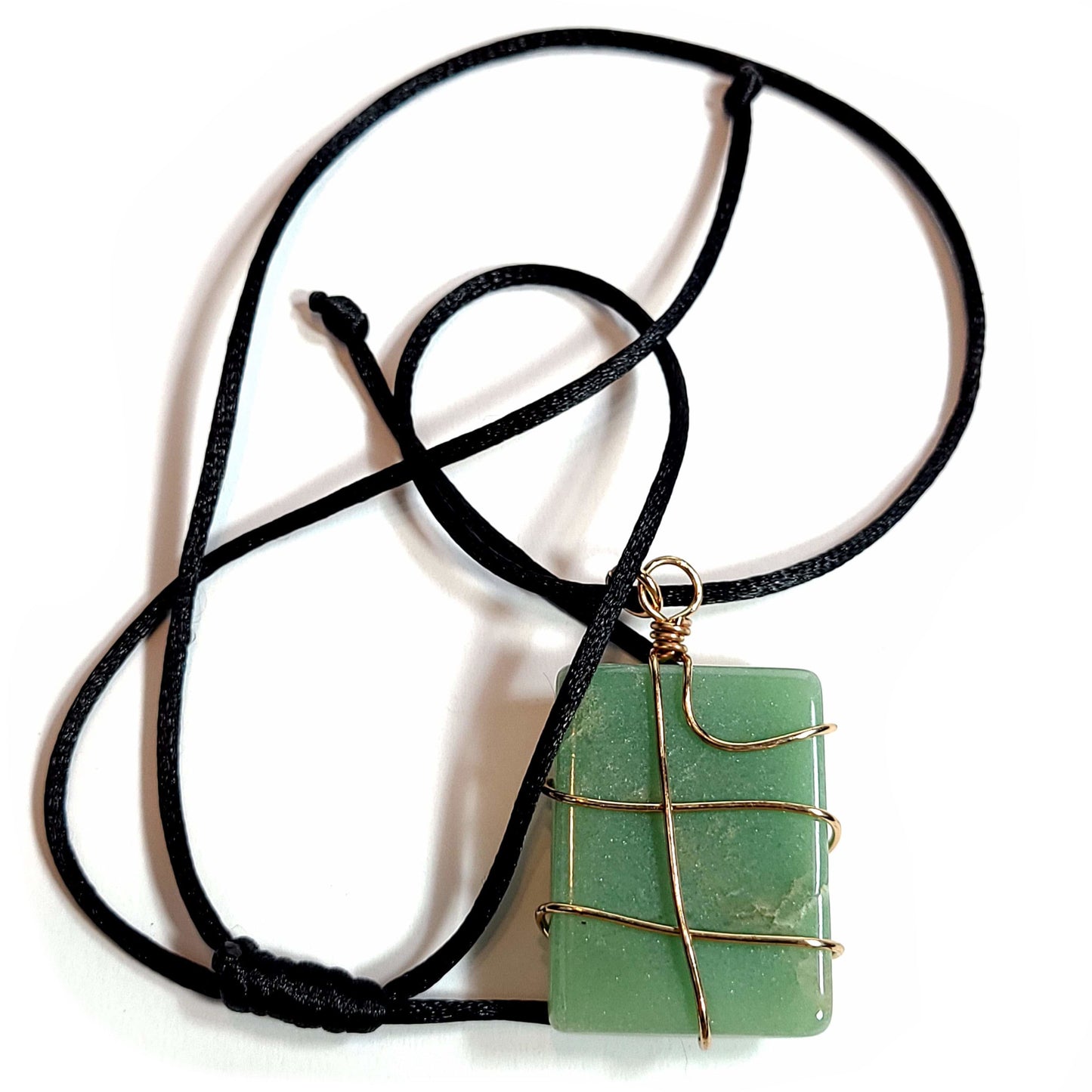 Rose gold colored wire wrapped Jade pendant with a black satin cord about with an adjustable slip knot.