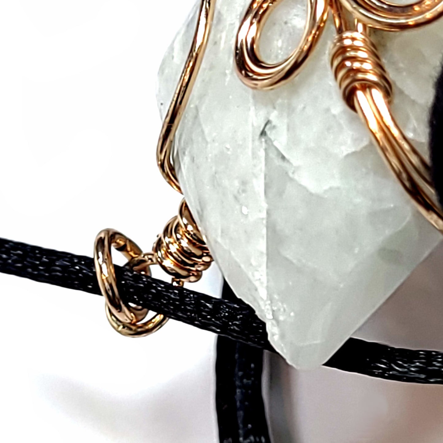 Rose wire wrapped Quartz pendant with tiny bits of black Tourmaline. Comes with a black satin cord with an adjustable slip knot. Stone has some minor natural pits and has a slight chip in the upper left corner.