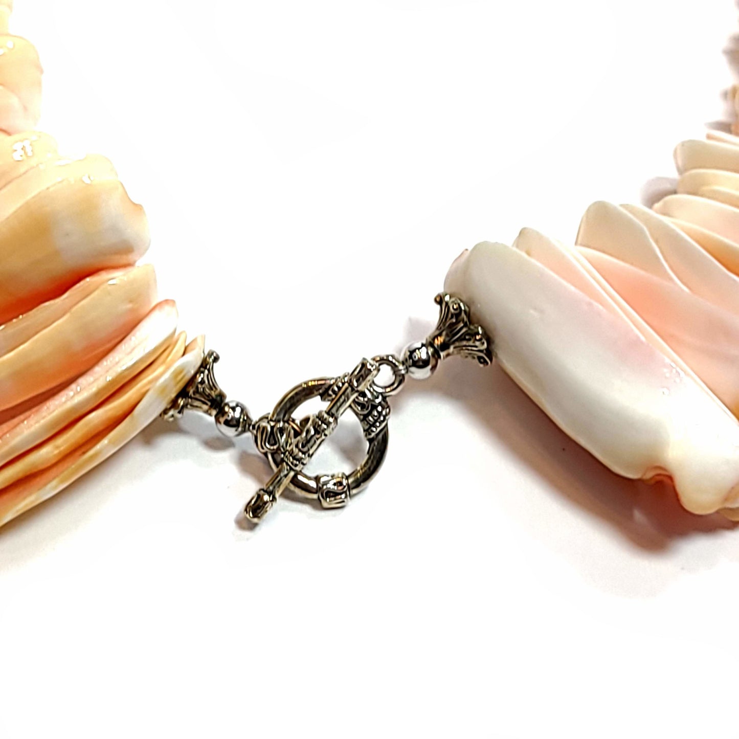 Close up of the toggle clasp on a handmade necklace made with vintage shells and three white 18mm beads.