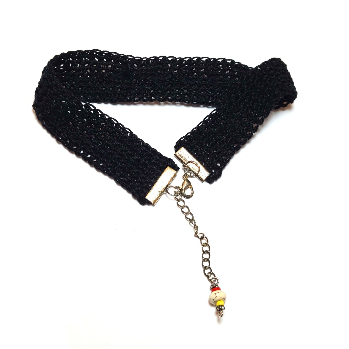 Back of a black crocheted choker with silver colored connectors, extension chain and decorative beads.