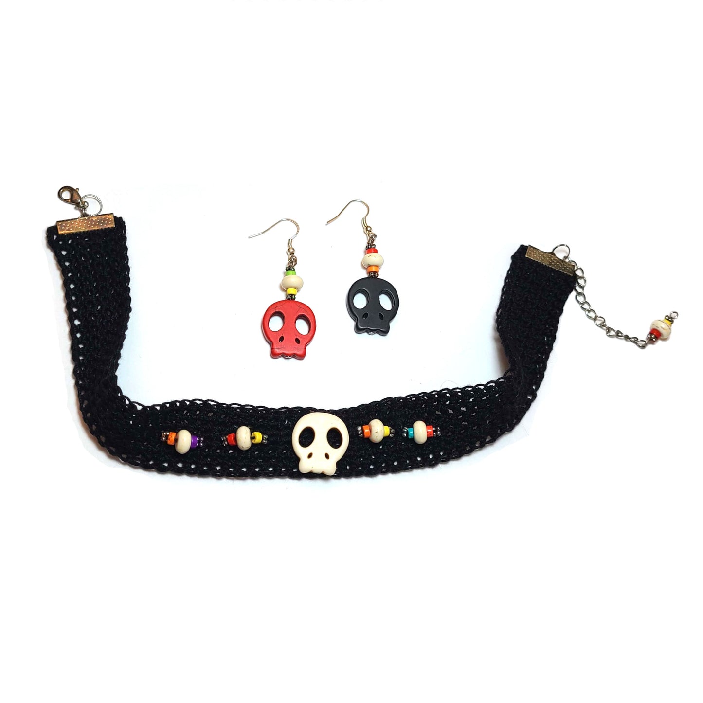 Black crocheted choker with white skull in center, flanked by decorative beads of blue, yellow, white, orange, and red, and silver spacers. A pair of earring with one skull each and decorative beads..
