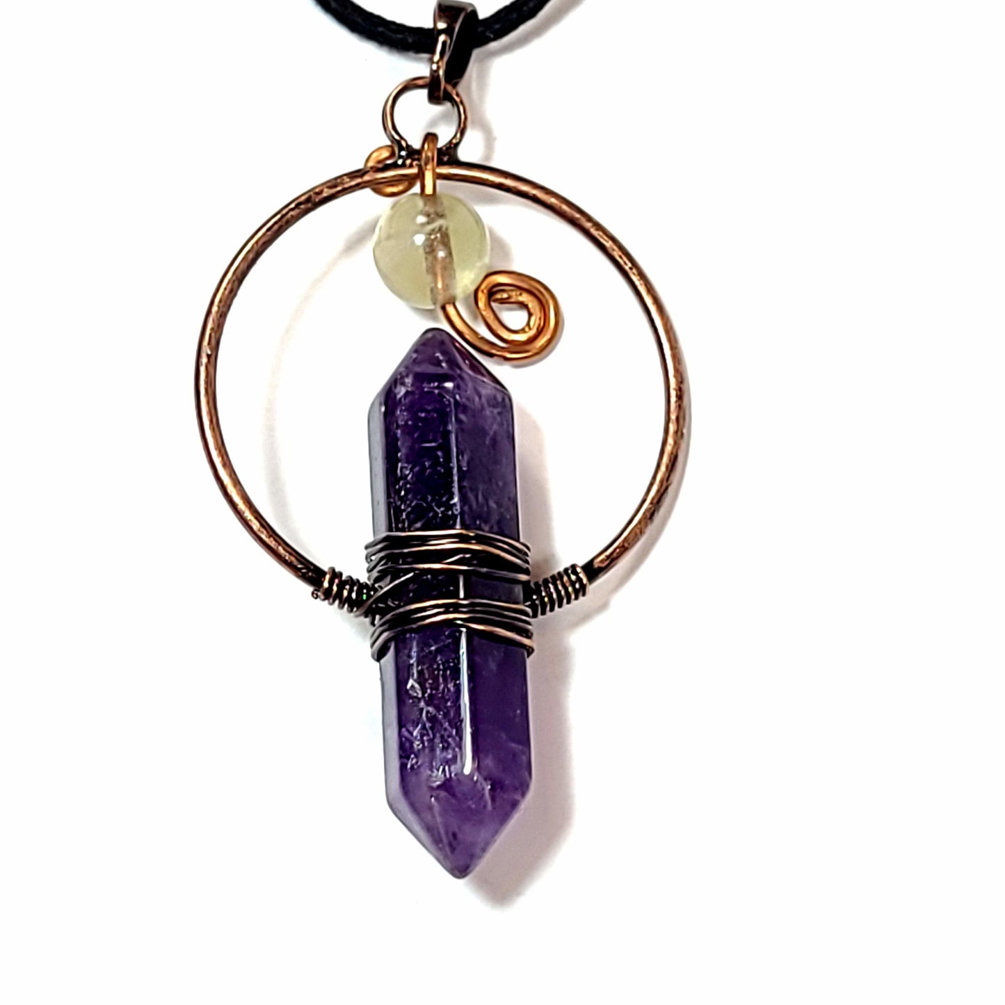 Close up of a dark purple amethyst crystal style pendant wrapped in copper with a floating quartz bead accent on a black leather necklace.