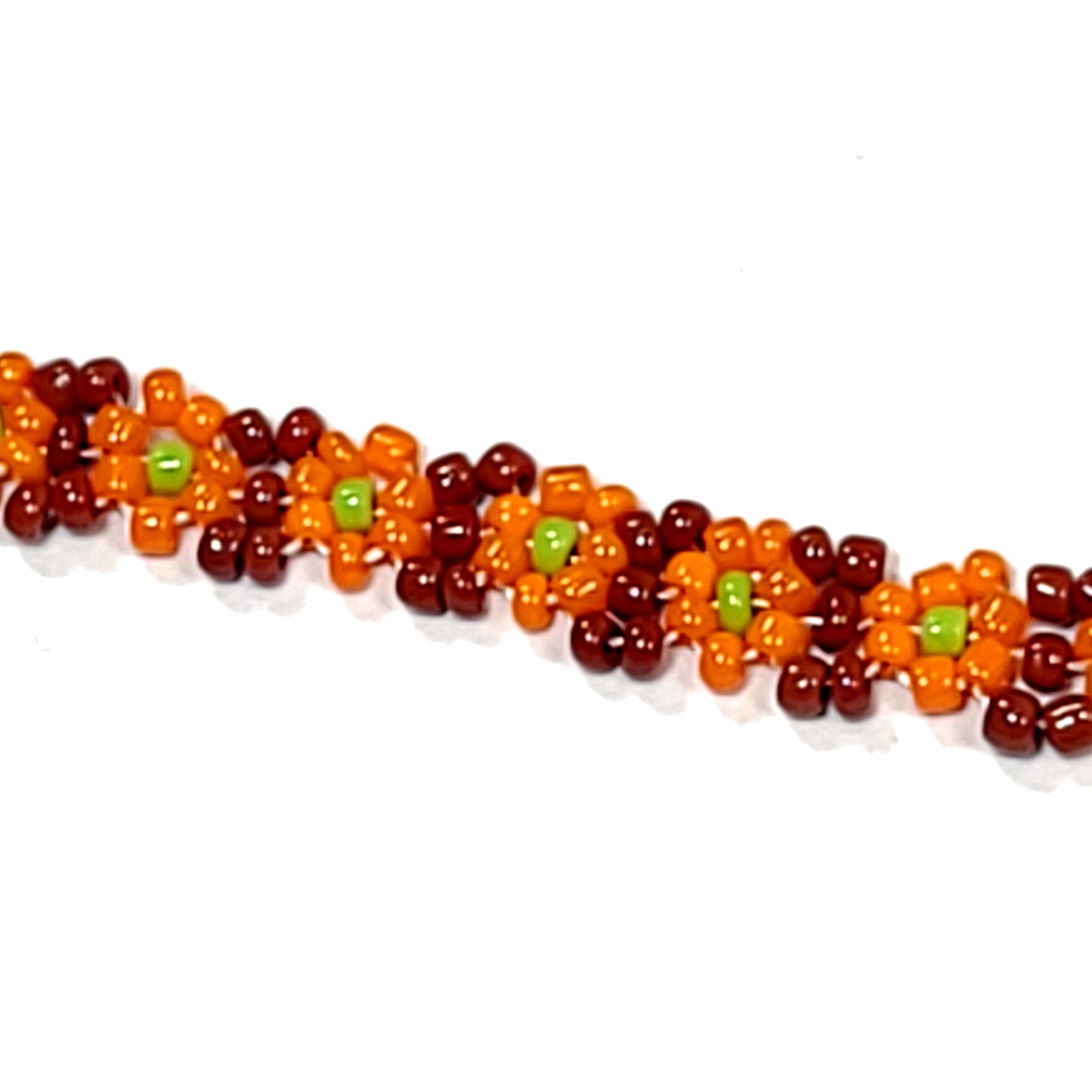 Close up of Orange daisy chain bracelet. Made with pumpkin orange flowers, lime green center, and brown background. Silver colored lobster claw clasp.