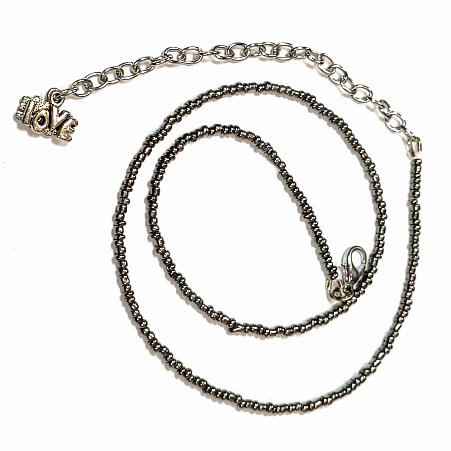 Single strand dark gray seed bead necklace with an extender that has 2 love charms on the end.