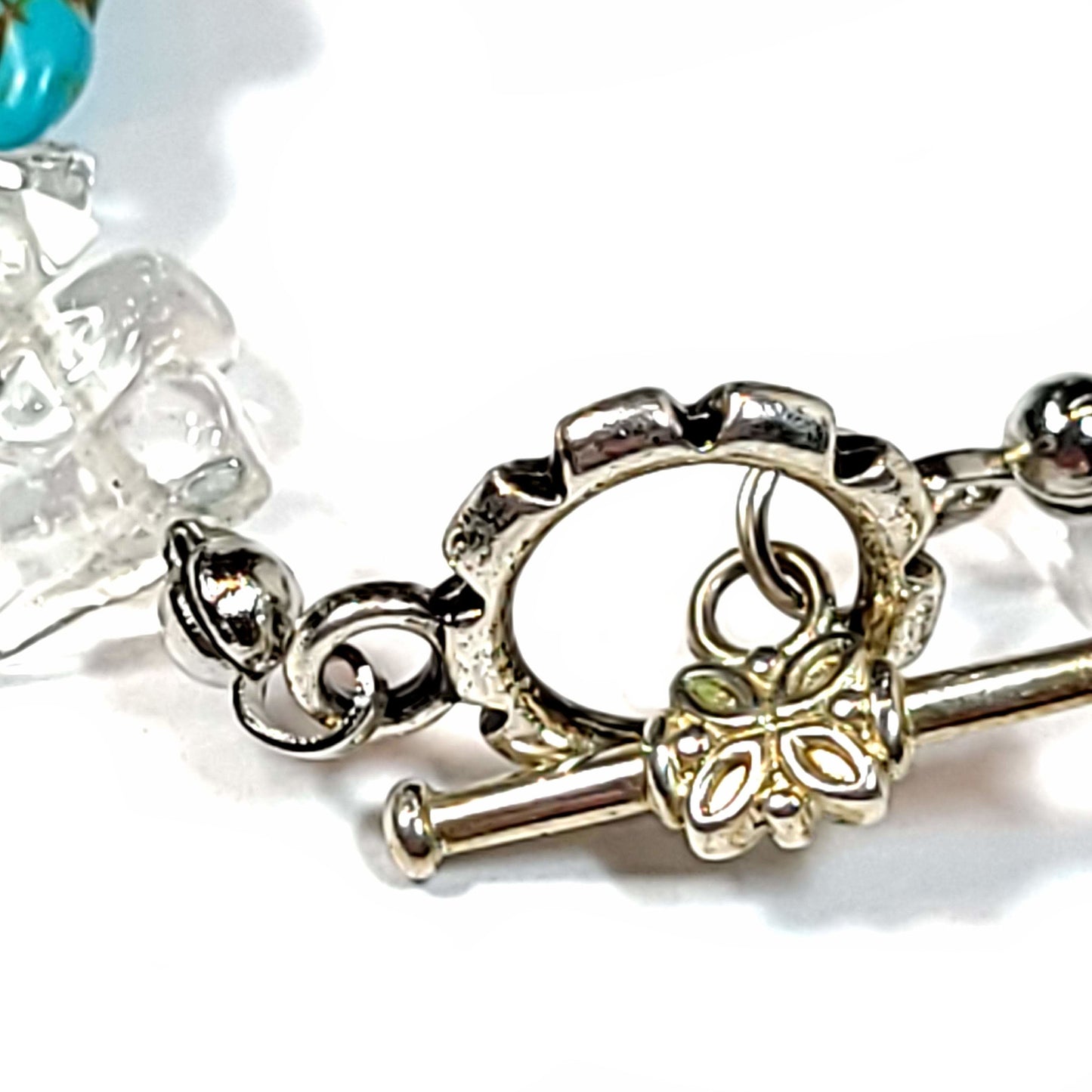 Bracelet made with rose quartz chips and howlite turtles with silver tone end caps, extender chain and toggle clasp.. Close up view of toggle clasp.