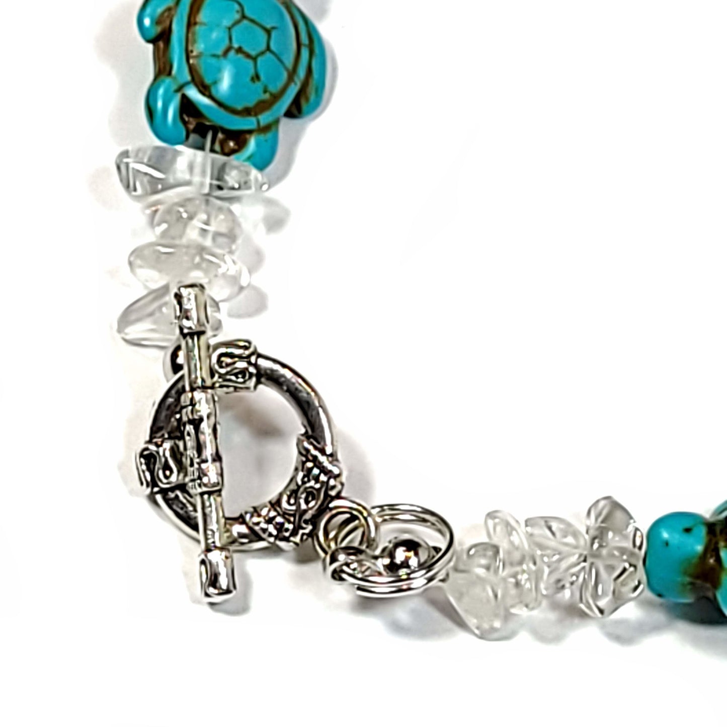 Close up view of the toggle clasp on a Bracelet made of Rose quartz chips and Howlite turtles with silver tone end caps.
