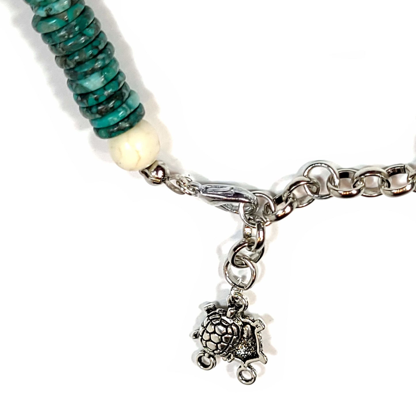 Close up of the clasp and turtle charms on Bracelet made of Chrysoprase flat disk beads with white Howlite turtle and highlight beads. Silver tone end caps, extender chain with 2 turtle charms attached and lobster claw clasp.