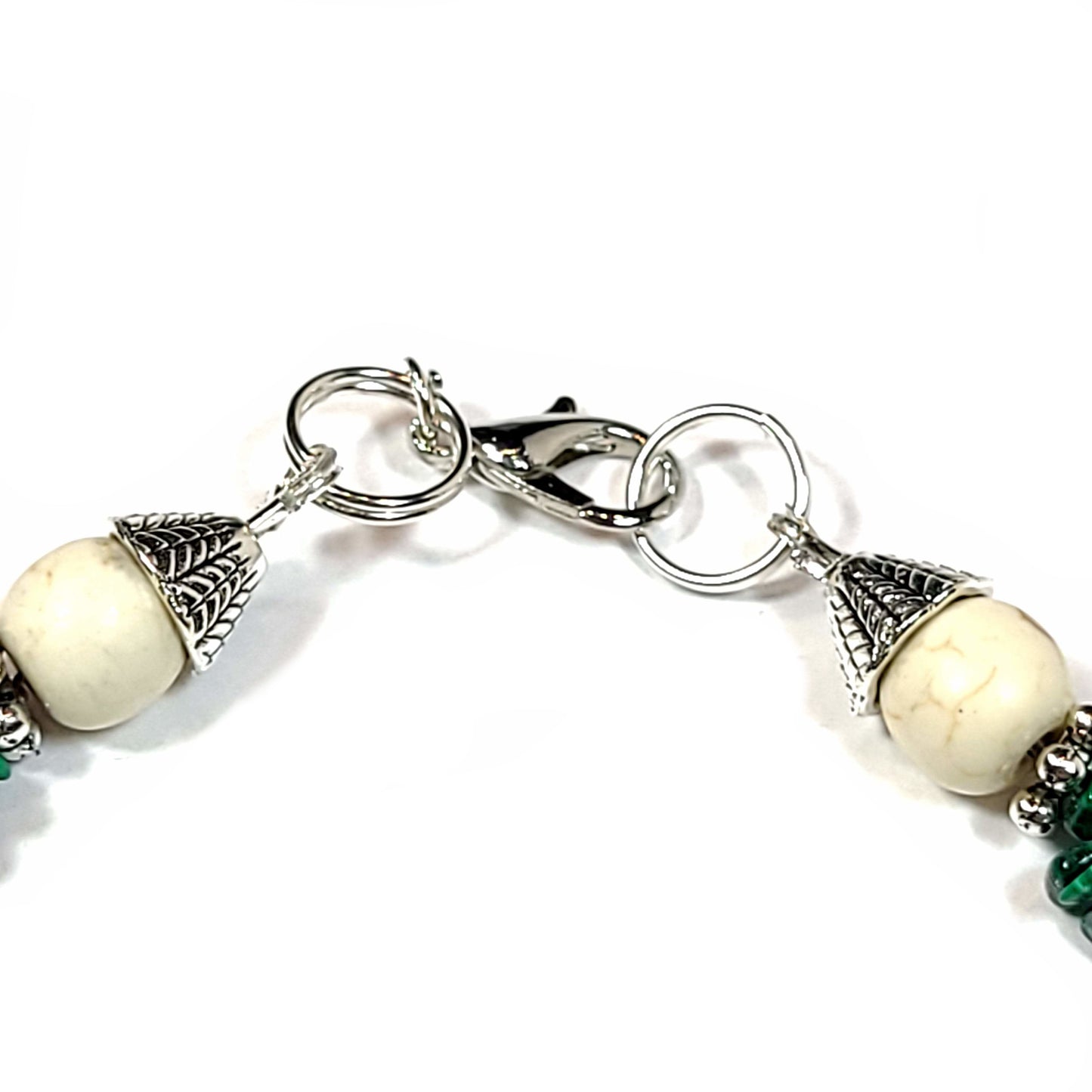 Close up view of the toggle clasp on a Earrings made of malachite chips, howlite beads, silver tone spacer beads, end caps and, lobster clasp.