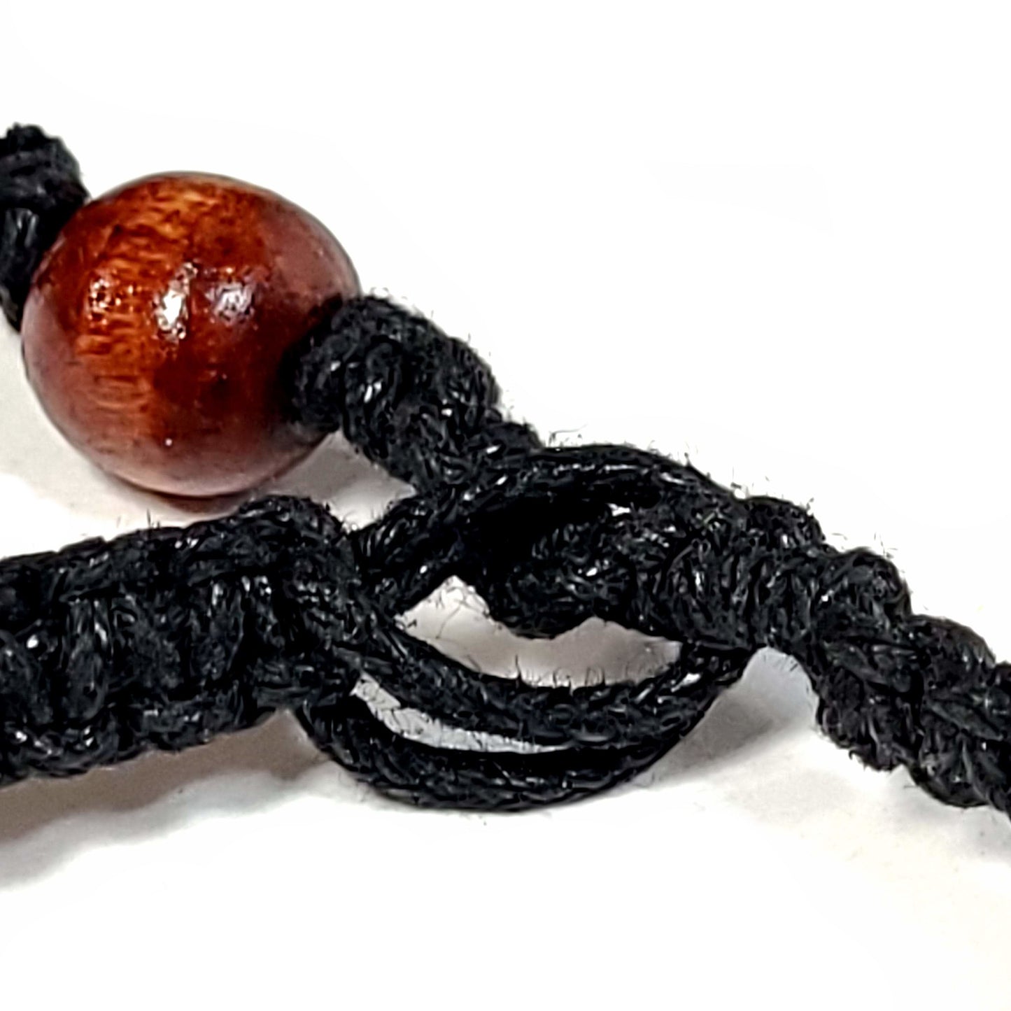 Close of of the clasp of a Black macrame bracelet with silver spacer beads and a wooden bead clasp.