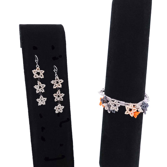 Beaded bracelet with dangly stars and earrings made of dangly stars on black velvet dispay stands.