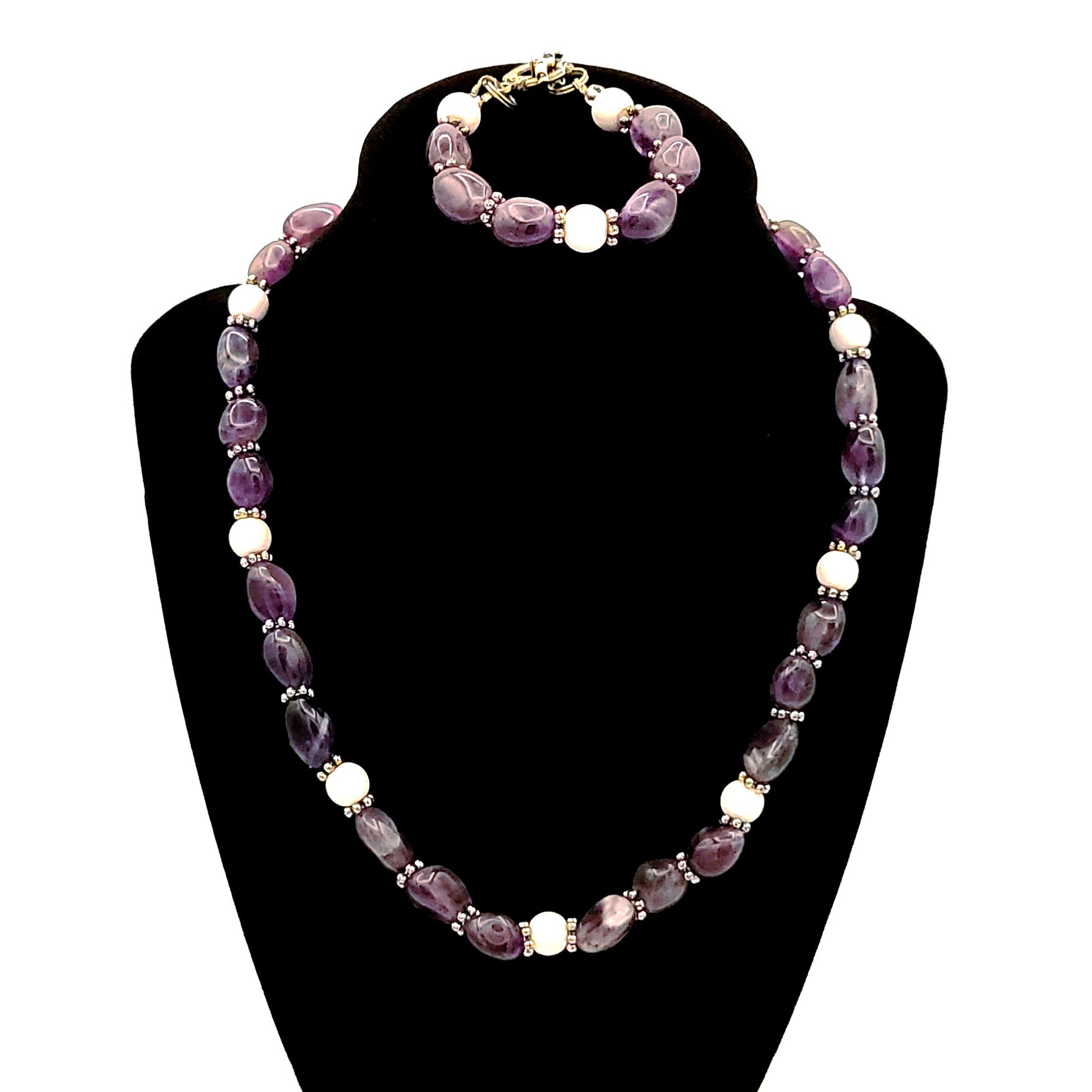 Necklace and bracelet made of amethyst pebble beads and white quartz beads with a silver color lobster clasp. on the necklace and a silver tone toggle clasp on the bracelet on a black velvet display.