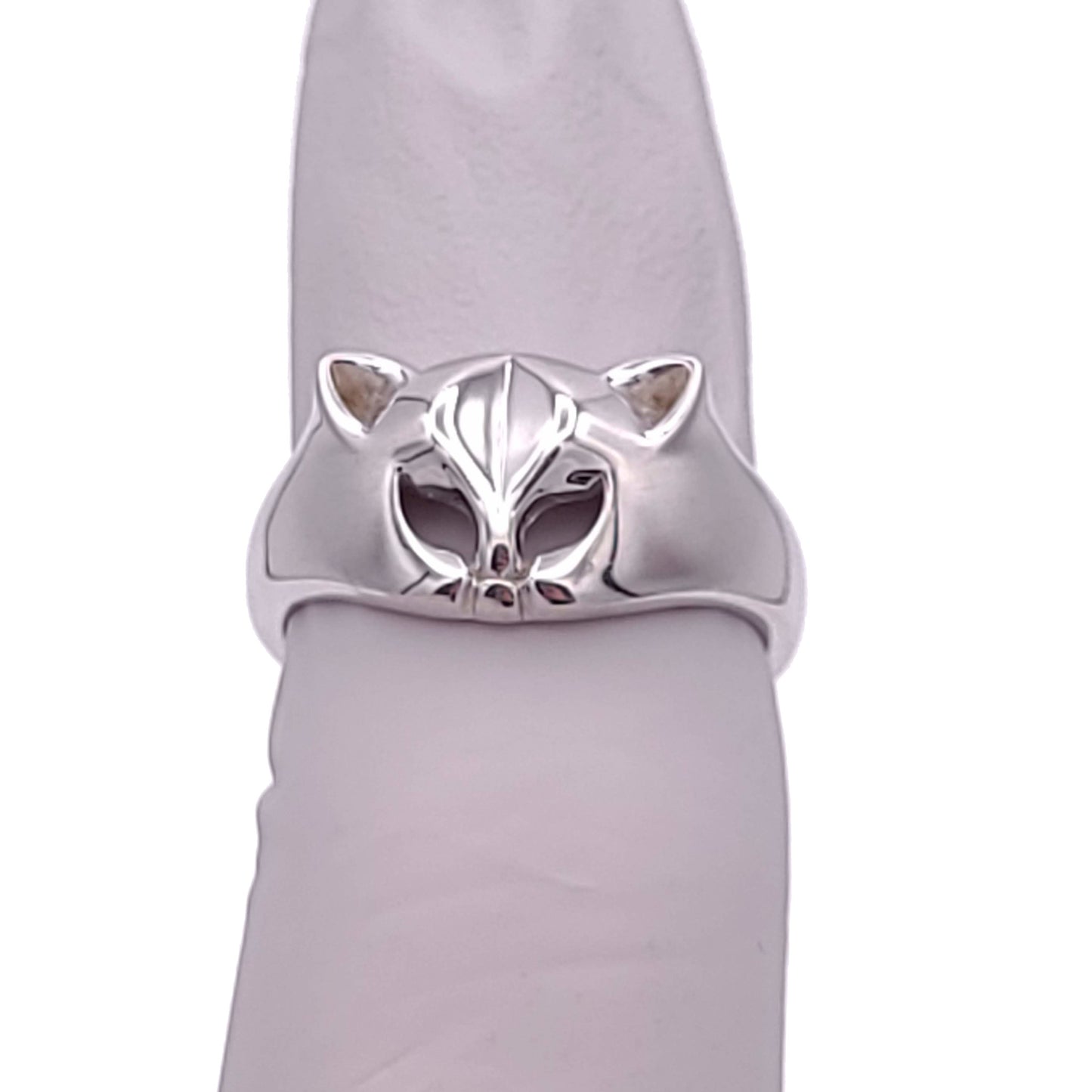 Silver ring with a cat face and ears. The eyes are cut outs of the metal. The ring is tapered down to the sides from the cat head. The inside of the band is stamped with "925." The ring is on a cylinder object.