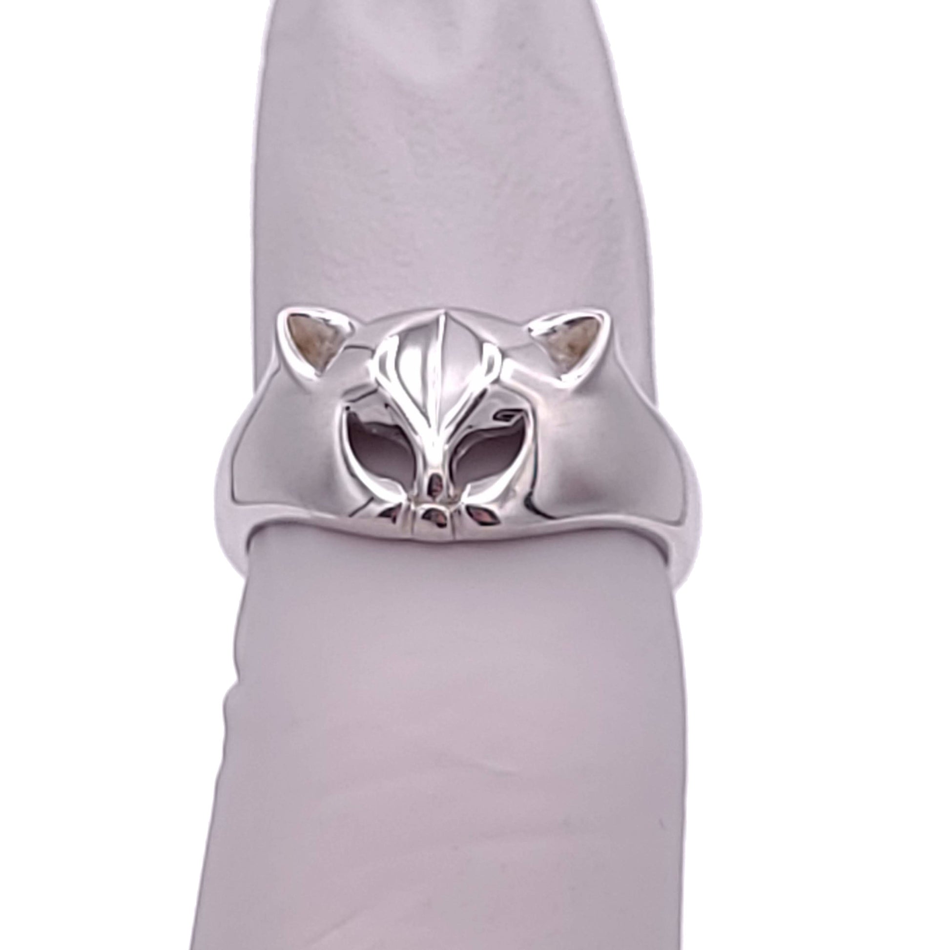 Silver ring with a cat face and ears. The eyes are cut outs of the metal. The ring is tapered down to the sides from the cat head. The inside of the band is stamped with "925." The ring is on a cylinder object.
