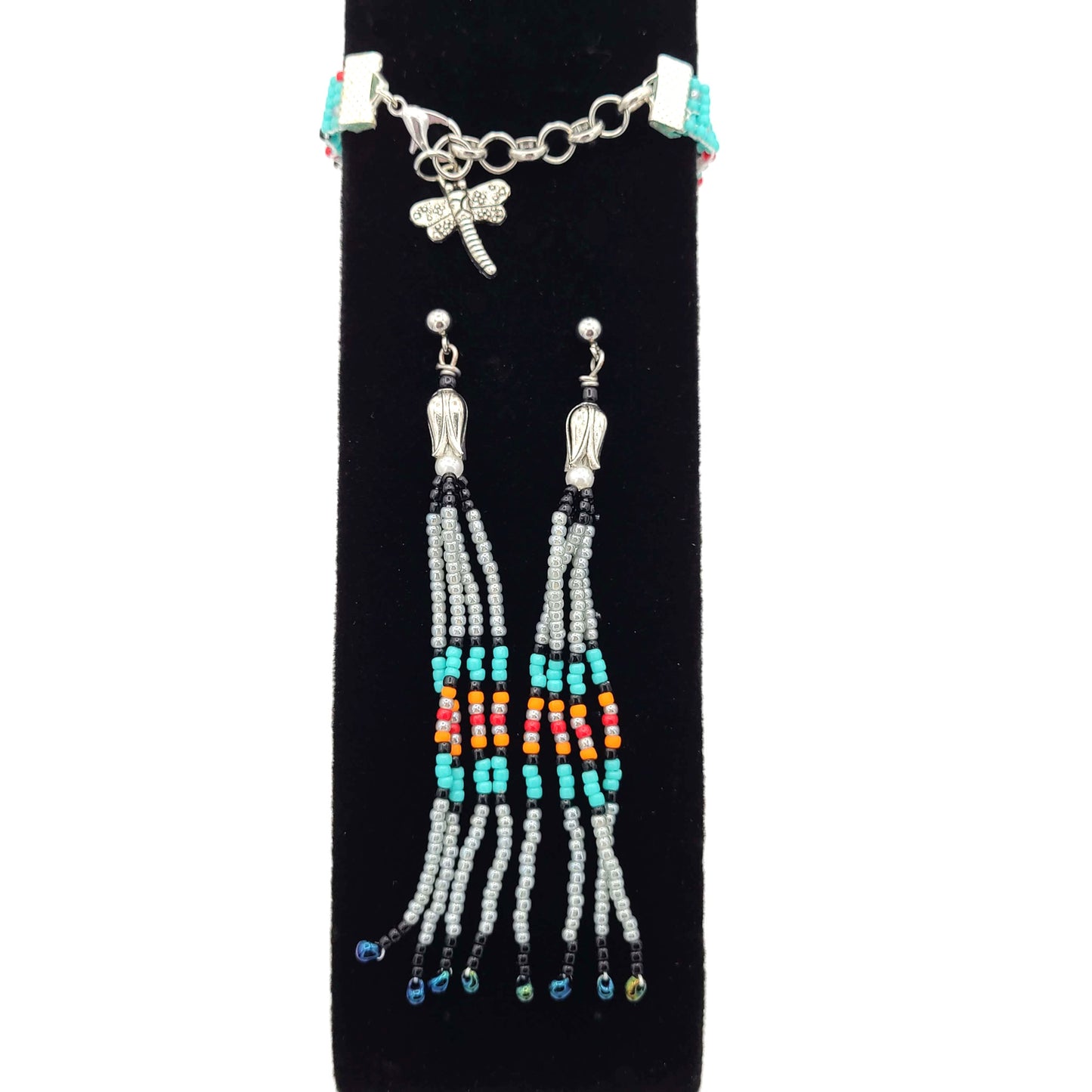 Fringe earrings of southwest colors and a matching bracelet with a dragonfly charm on a black velvet display.