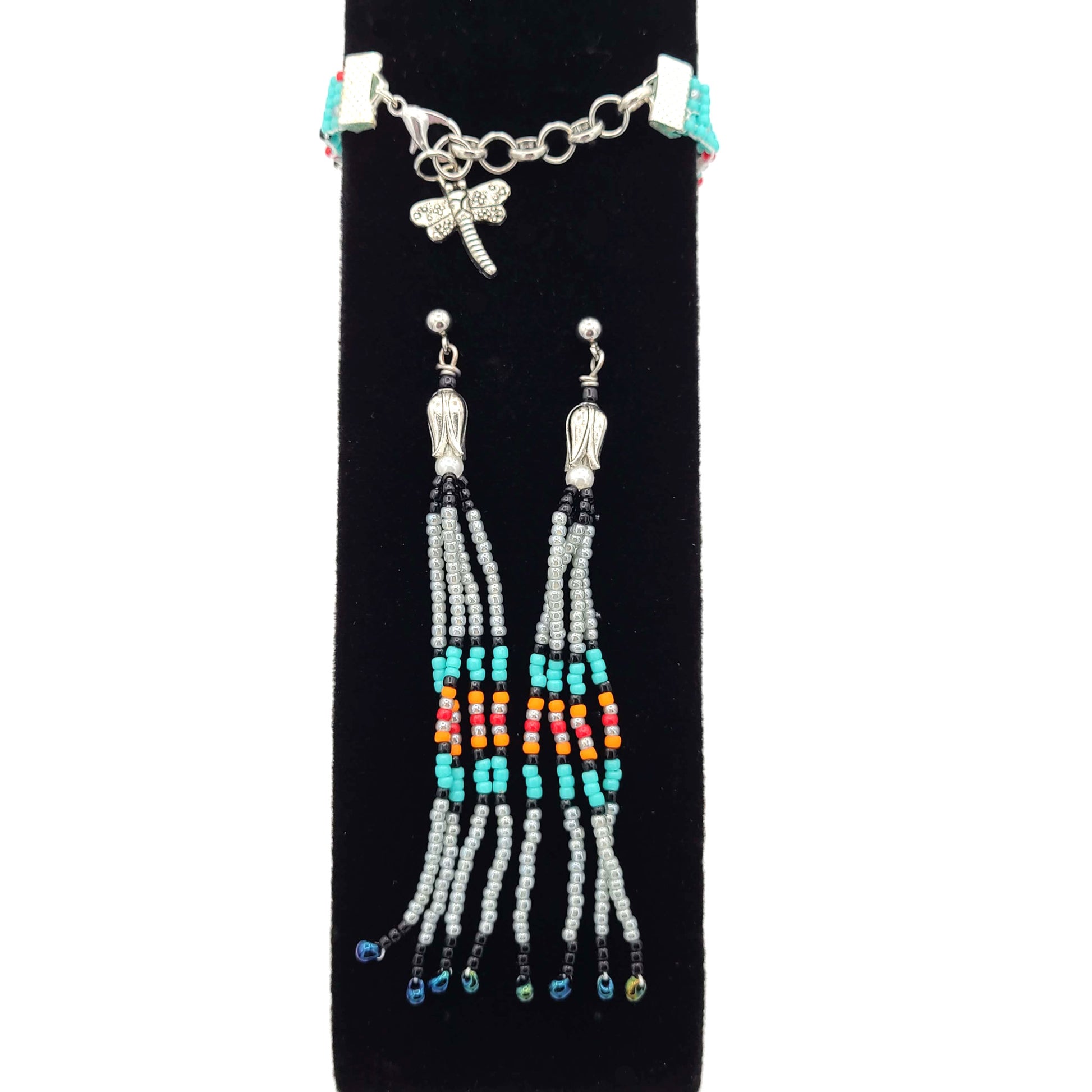 Fringe earrings of southwest colors and a matching bracelet with a dragonfly charm on a black velvet display.