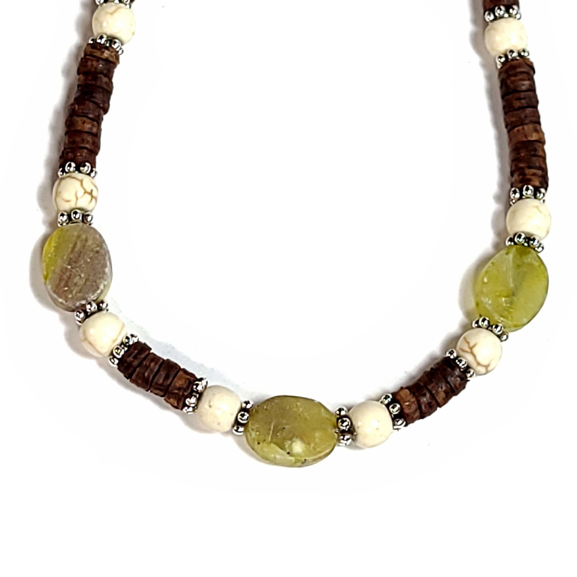 Close up of a handmade necklace with heshi shaped coconut shell beads, howlite beads, and matte green fluorite beads highlighted with silver tone spacer beads. End caps are silver tone with lobster clasp and an extender chain.