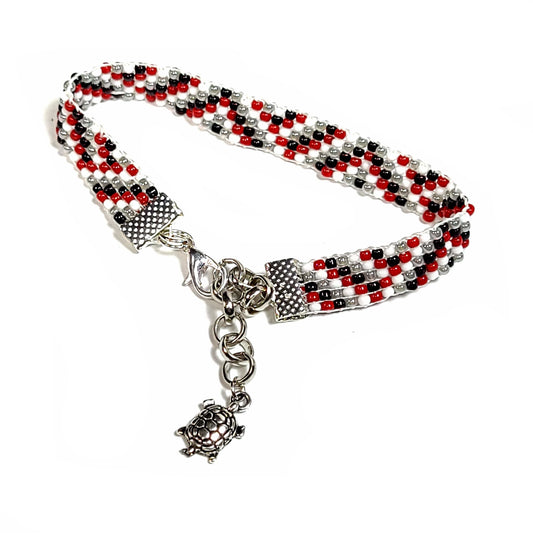Woven handmade seed bead bracelet with red, white, black and light gray seed beads. Silver toned end clips with silver toned lobster clasp and silver toned turtle charm.