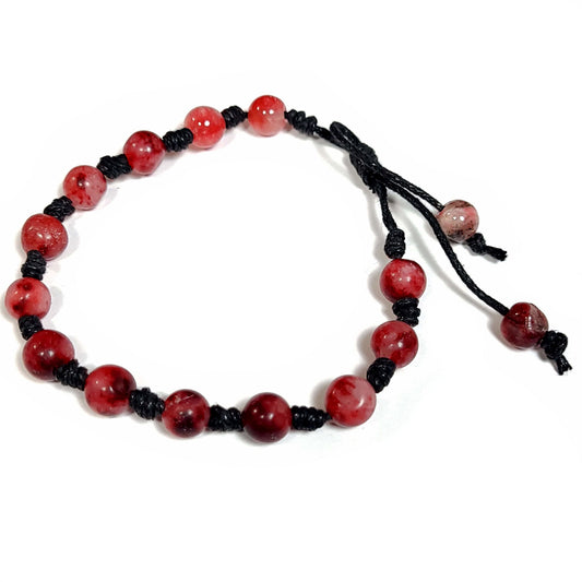 Handmade knotted bracelet of red stone beads with white and a little black running through them, Can be worn as a bracelet or anklet. Adjustable slip knot makes adjusting