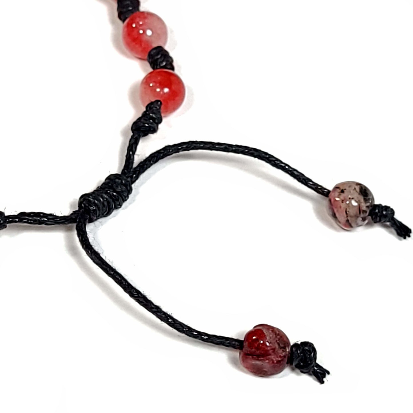 Close up of the adjustable knot on a Handmade knotted bracelet of red stone beads with white and a little black running through them, Can be worn as a bracelet or anklet. Adjustable slip knot makes adjusting