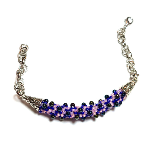 bracelet made of lilac, purple, royal blue, and iridescent black beads with silver color end caps and chain.