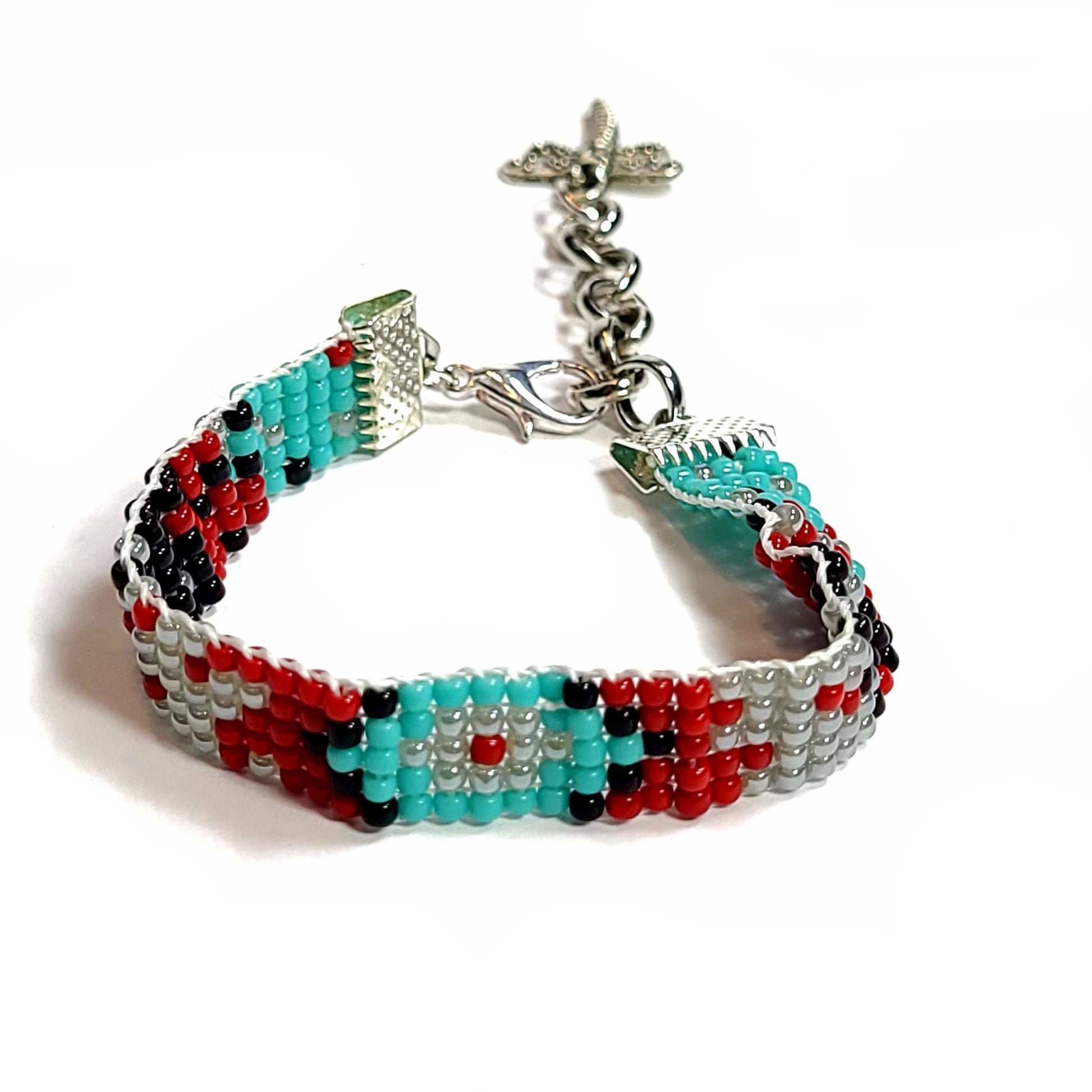 Woven seed bead bracelet with turquoise, black, light gray, red beads. Silver tone end clamps, lobster claw, extender chain, and dragonfly charm.