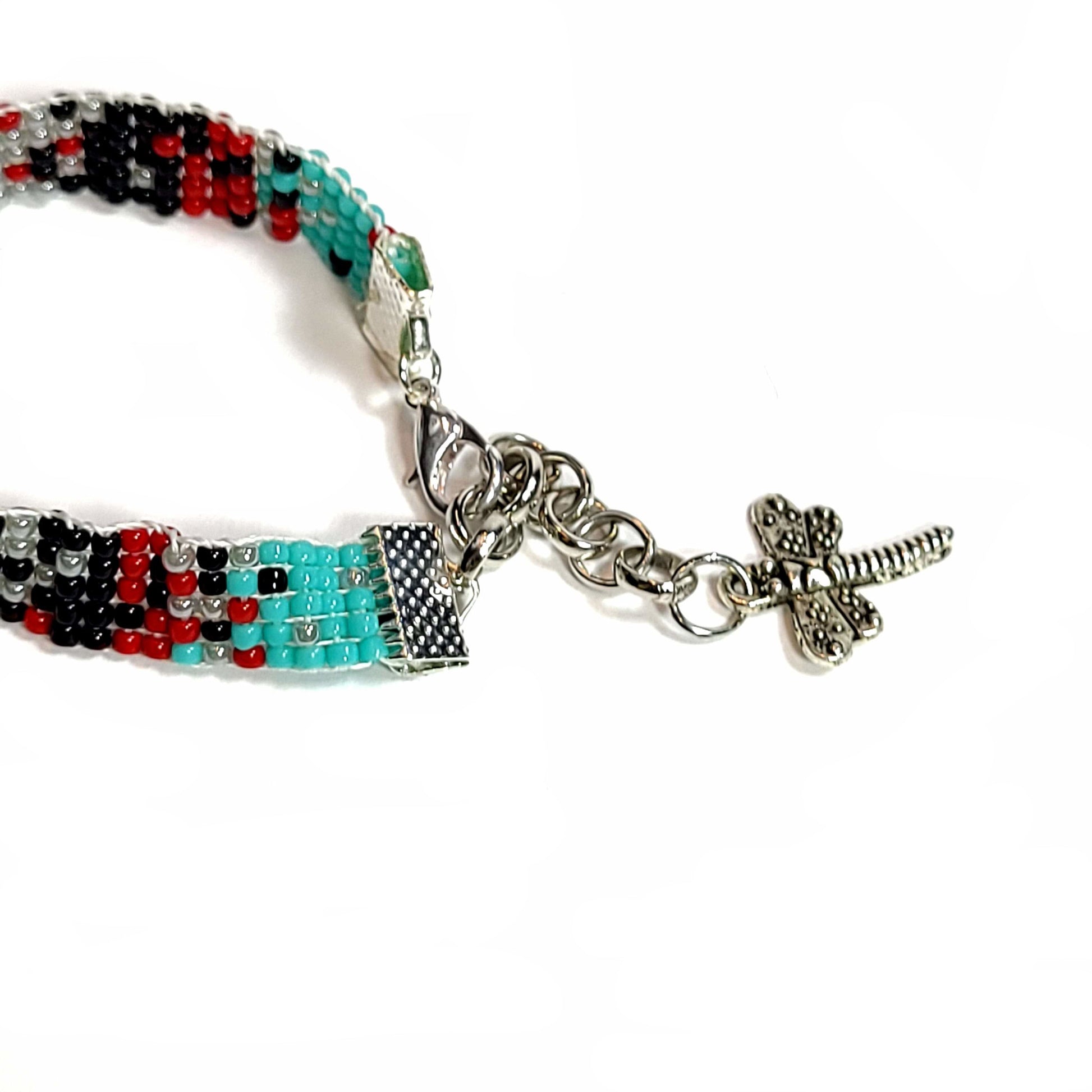 Woven seed bead bracelet with turquoise, black, light gray, red beads. Silver tone end clamps, lobster claw, extender chain, and dragonfly charm.