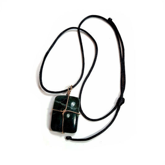 Rose gold colored wire wrapped dark green Jasper stone. Comes with a black satin cord with an adjustable slip knot. Stone has a natural imperfection on the face.