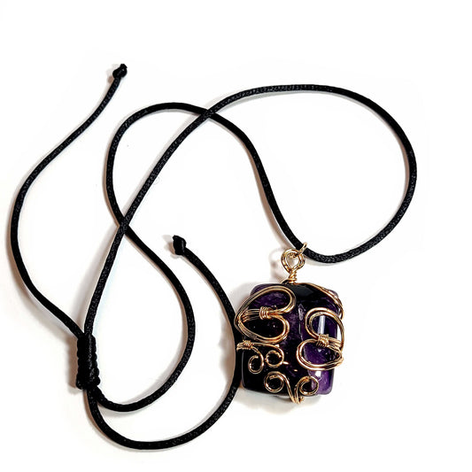 Rose gold colored wire wrapped Very Dark Purple Amethyst. Comes with a black satin cord with an adjustable slip knot.