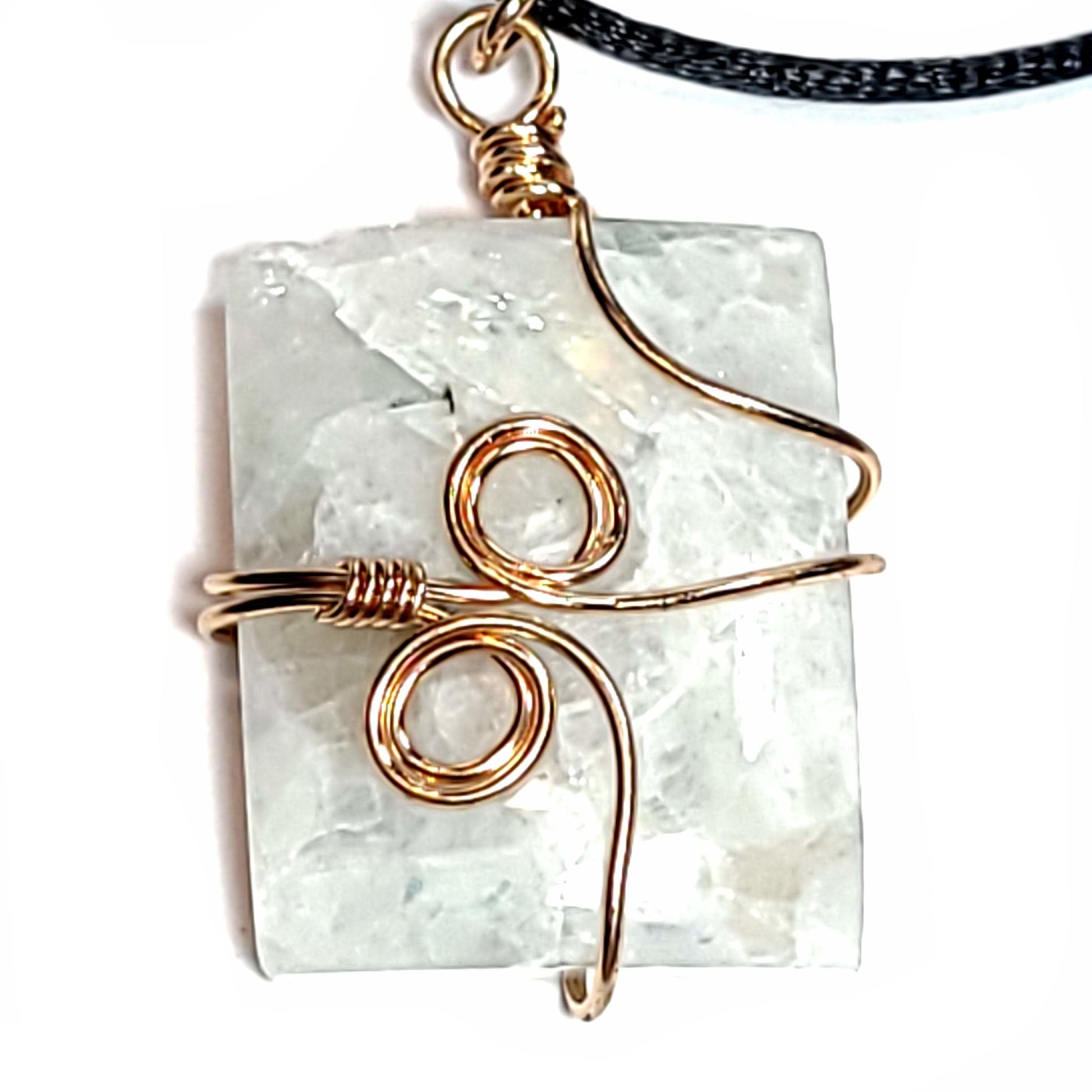 Rose wire wrapped Quartz pendant with tiny bits of black Tourmaline. Comes with a black satin cord with an adjustable slip knot. Stone has some minor natural pits and has a slight chip in the upper left corner.
