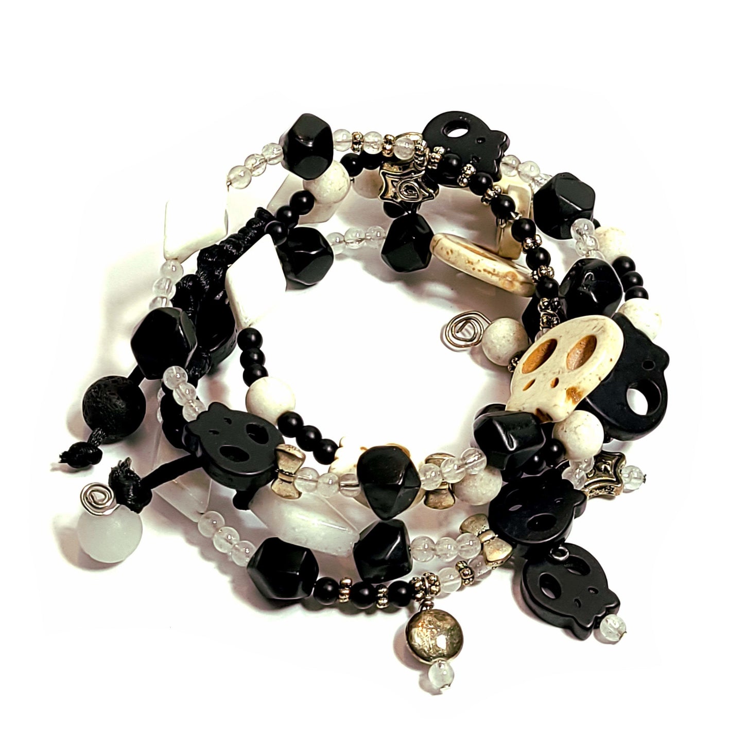 memory wire bracelet made with silver color bow, disc, and star charms, black and white color skull beads, white triangle beads, and smaller black and white beads.
