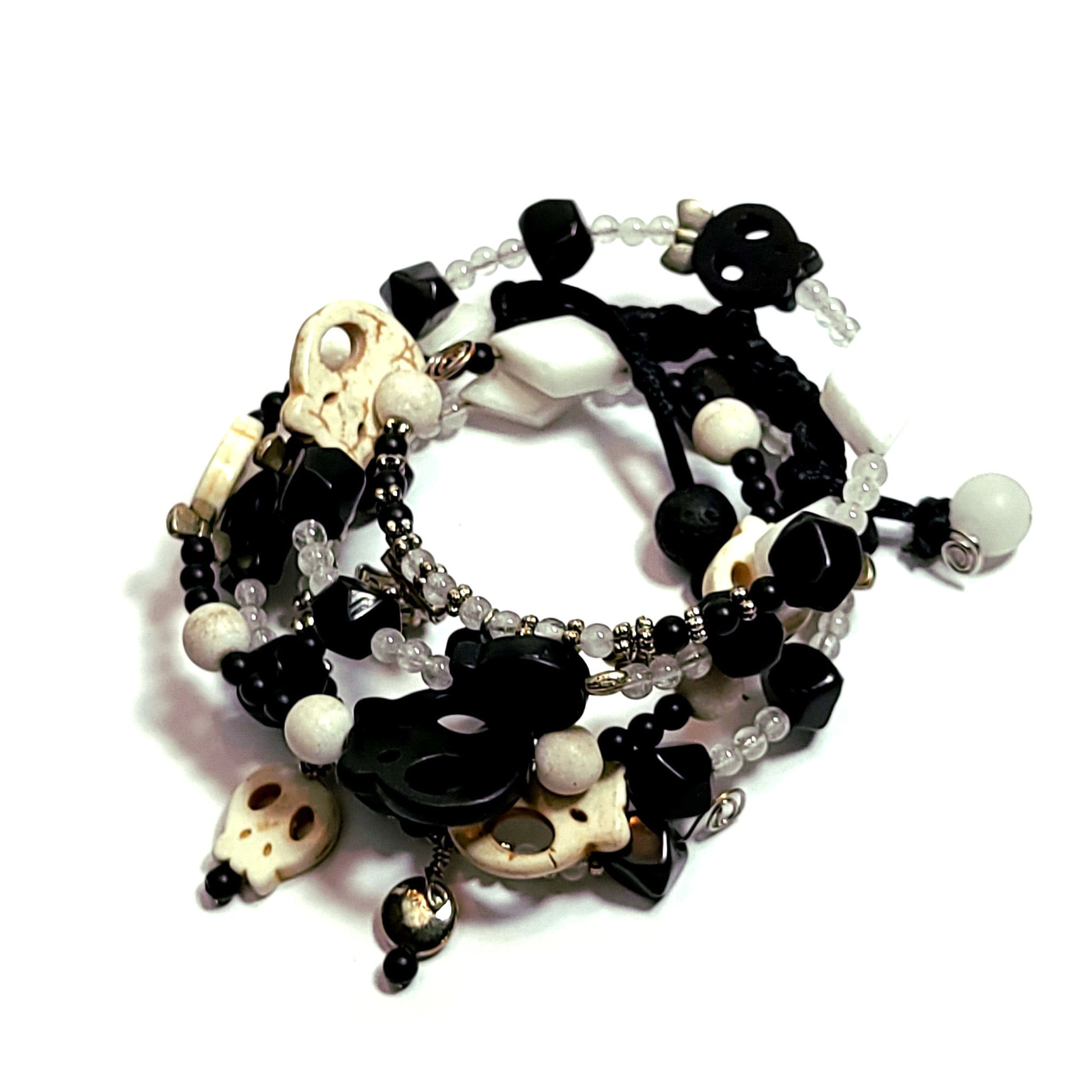 memory wire bracelet made with silver color bow, disc, and star charms, black and white color skull beads, white triangle beads, and smaller black and white beads.