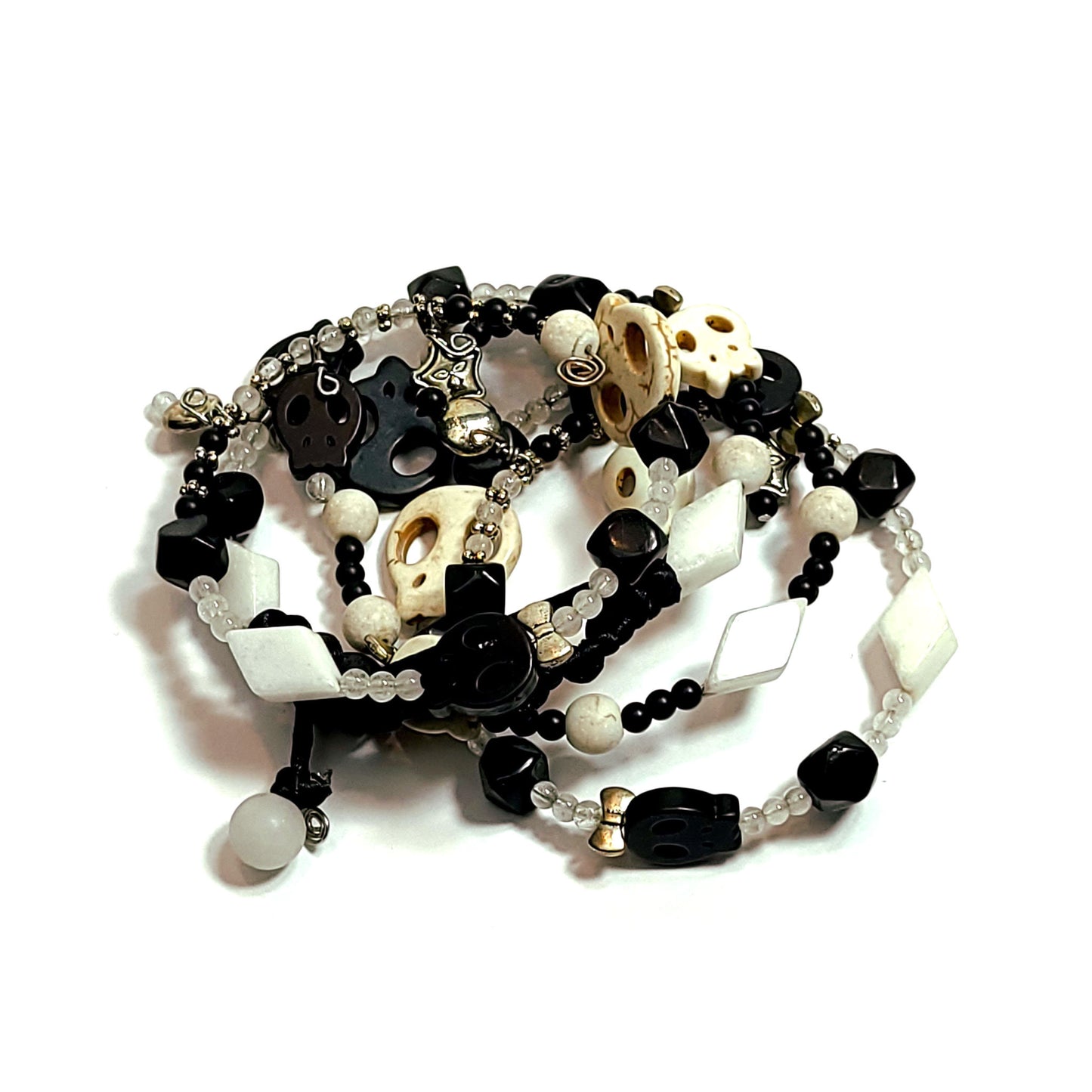 memory wire bracelet made with silver color bow, disc, and star charms, black and white color skull beads, white triangle beads, and smaller black and white beads.
