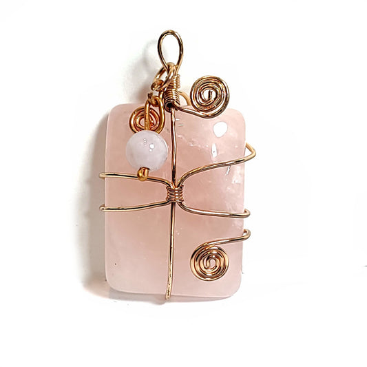 Rose quartz stone pendant wrapped with rose gold plated wire. Crowned with a rose quartz and distressed copper wire floating charm.
