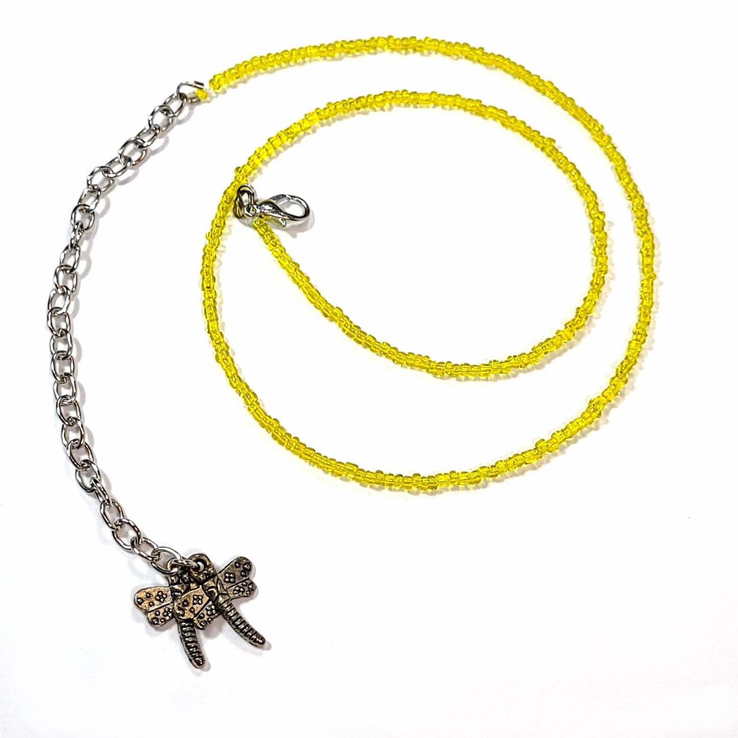 Single strand yellow seed bead necklace with an extender that has 2 dragonfly charms on the end.