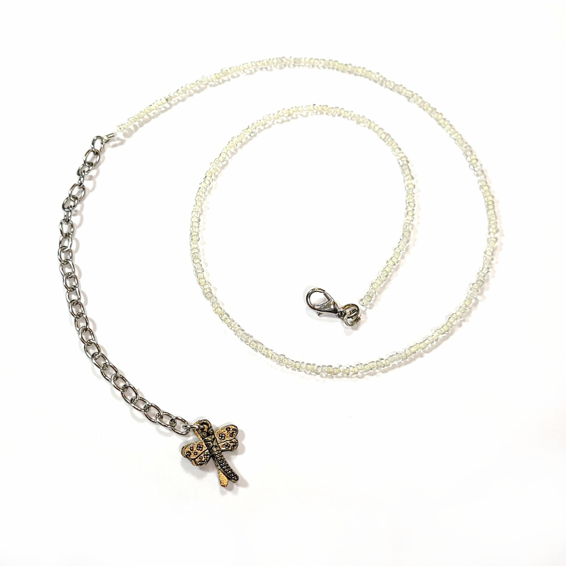 Single strand white seed bead necklace with an extender that has 2 dragonfly charms on the end.