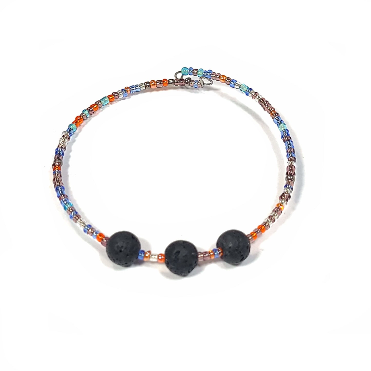 Bracelet and earring set made of multi-color seed beads in the blue and orange color range. The bracelets (2) are singular memory wire with triple lava rock center pieces. Small hoop earrings drop approximately. View of bracelet with black lave rocks.