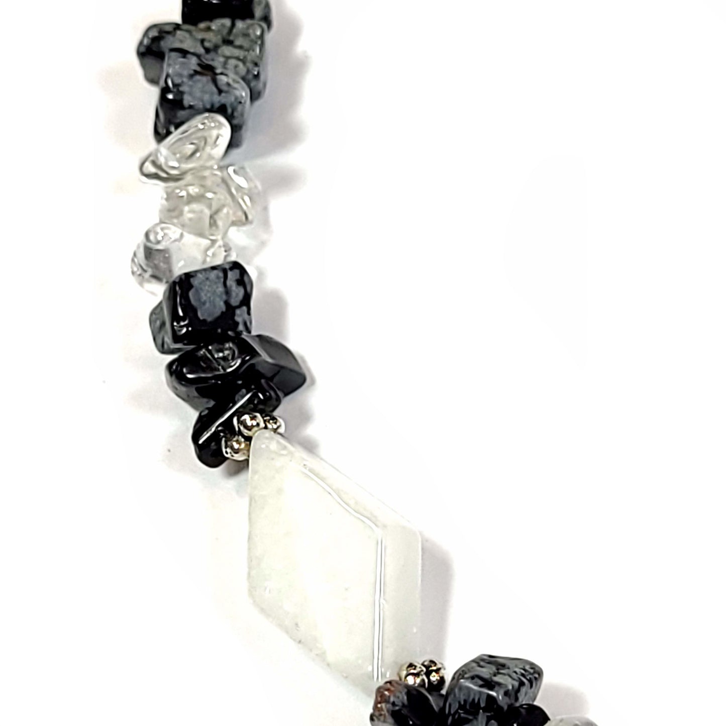 Necklace made of White quartz diamond beads, with crystal quartz chips and Snowflake Obsidian highlighted with silver tone spacer beads and bar and loop toggle clasp. Close up view.