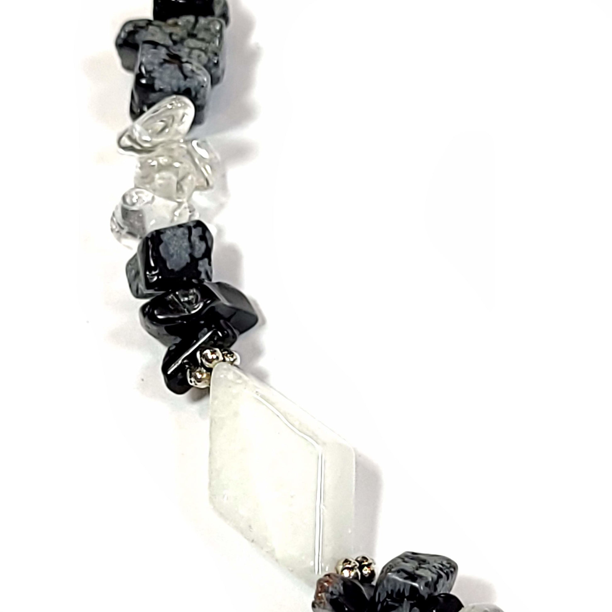 Necklace made of White quartz diamond beads, with crystal quartz chips and Snowflake Obsidian highlighted with silver tone spacer beads and bar and loop toggle clasp. Close up view.