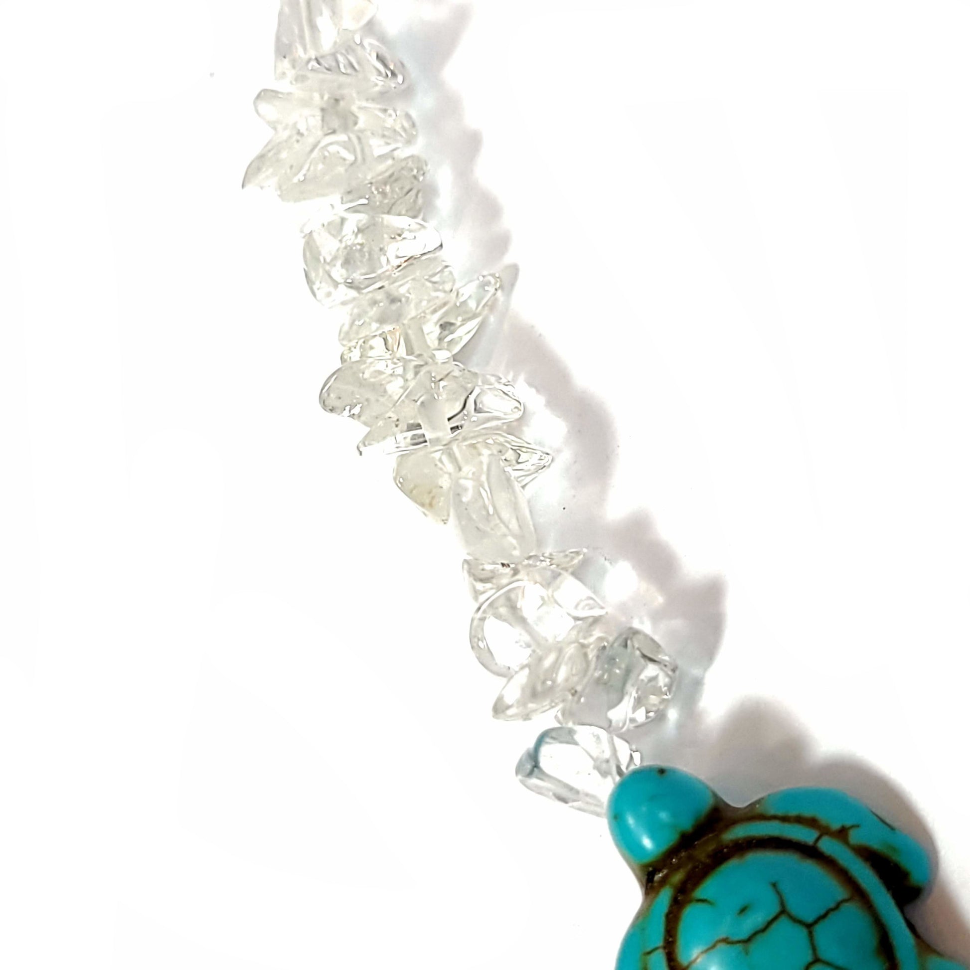 Close up view of a Necklace made of crystal quartz chips with aqua dyed howlite, and end caps with a silver tone extender chain and lobster clasp.