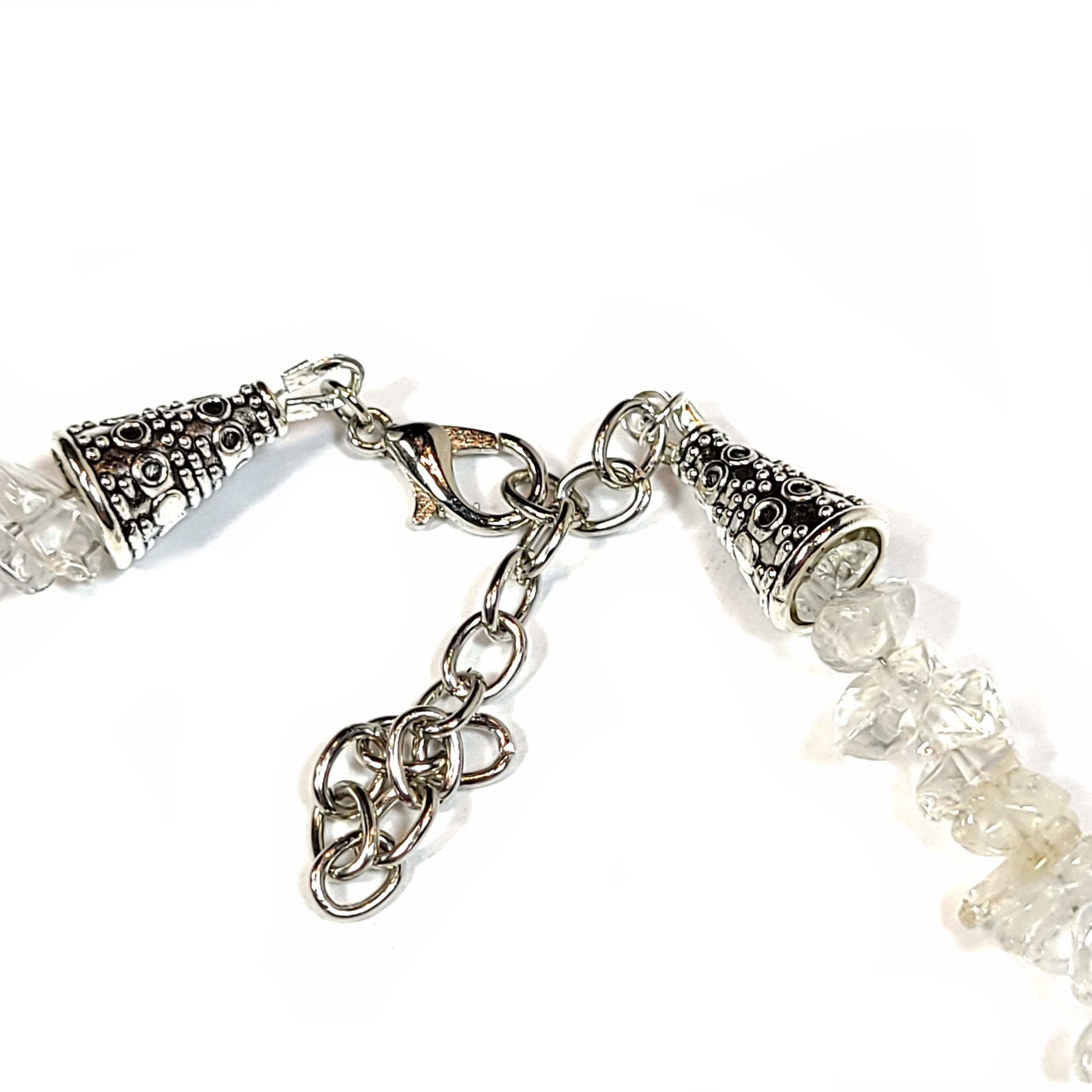 Close up view of the clasp on a Necklace made of crystal quartz chips with aqua dyed howlite, and end caps with a silver tone extender chain and lobster clasp.