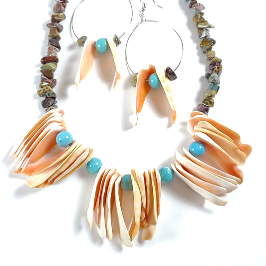 Handcrafted Necklace with vintage peach colored shells, 5 turquoise colored beads alternating with about 5 of the shells, and mulitcolored jasper chip beads necklace. Two handcrafted silver colored wire hoop earrings with a jasper chip bead, a vintage shell, a turquoise bead, another vintage shell, and another jasper chip bead. The necklace and earring match and are made with the same materials